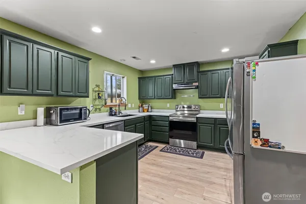 a kitchen with a refrigerator a stove top oven a sink and cabinets