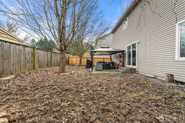 a view of a backyard with large trees and wooden fence