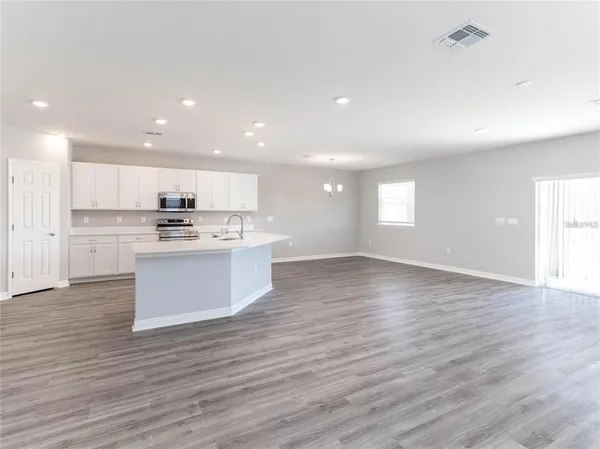 a view of kitchen with kitchen island wooden floors and stainless steel appliances