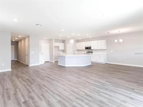 a view of kitchen with kitchen island wooden floor appliances and living room