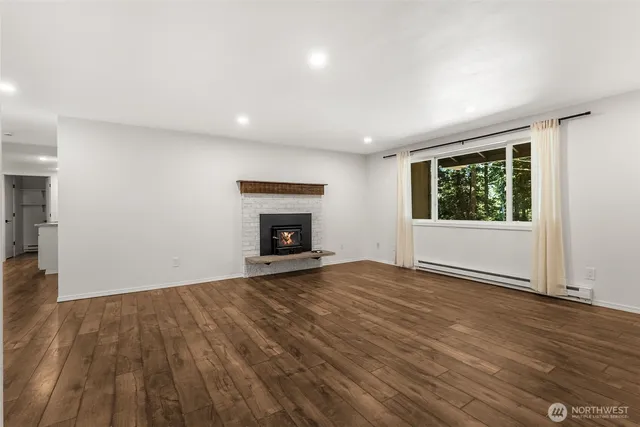 a view of empty room with wooden floor and fireplace