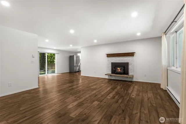 an empty room with wooden floor fireplace and windows