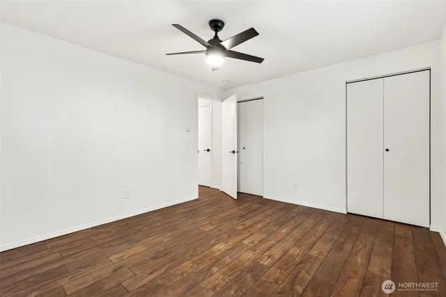 an empty room with wooden floor and ceiling fan