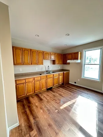 a large kitchen with stainless steel appliances wooden floors and large window