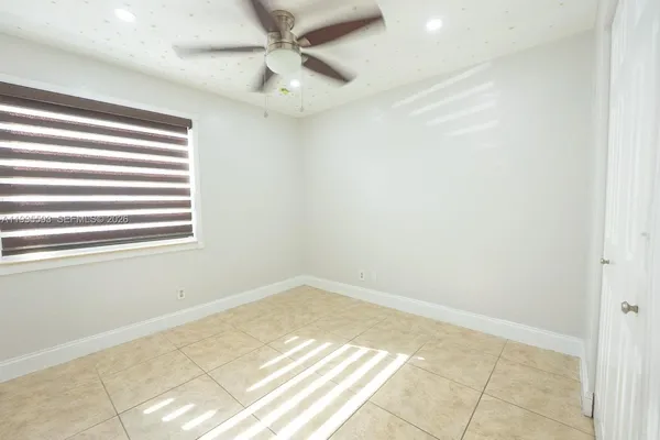 an empty room with a ceiling fan and window