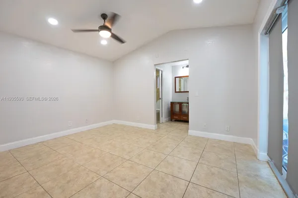 an empty room with chandelier fan and windows