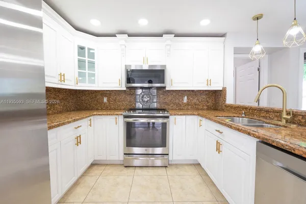 a kitchen with stainless steel appliances granite countertop a stove a sink and a granite counter tops with white cabinets