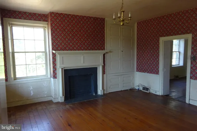 an empty room with wooden floor windows and fireplace