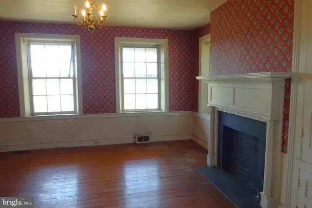 an empty room with windows and fireplace