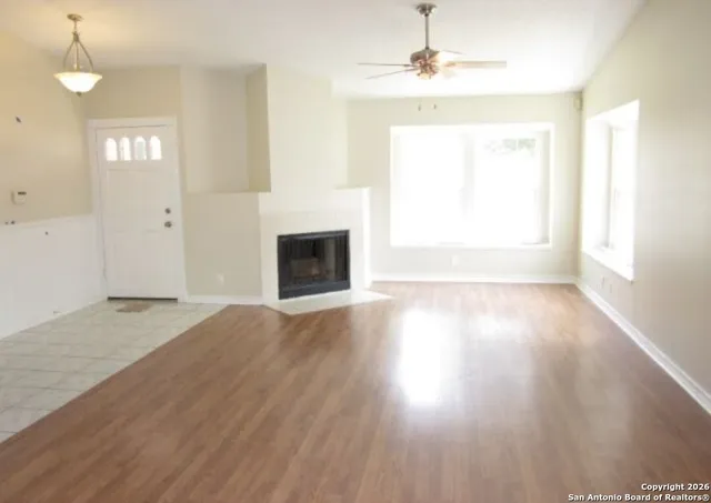 an empty room with wooden floor fireplace and windows
