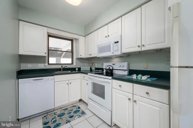 a kitchen with granite countertop white cabinets and white appliances