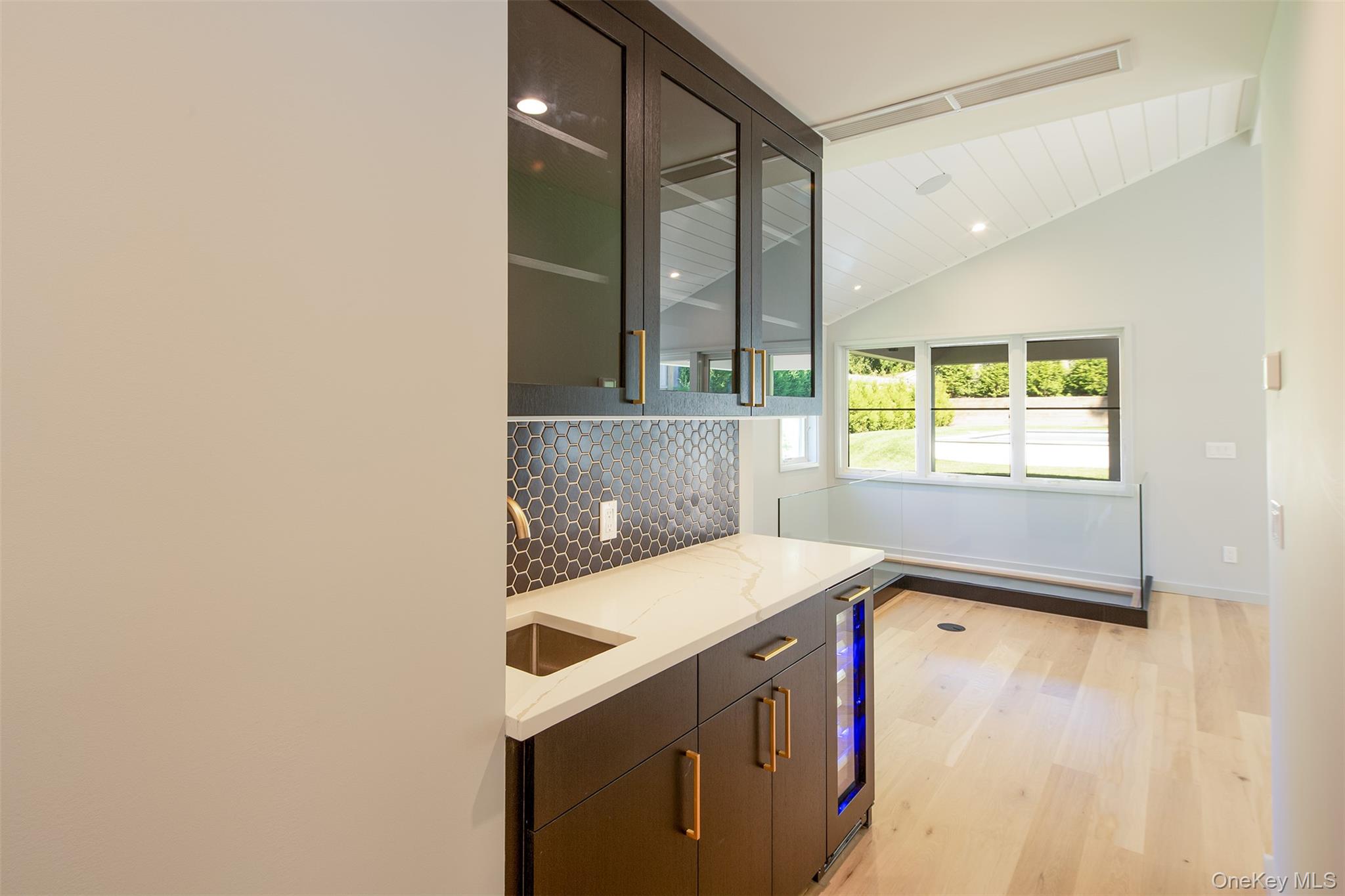 195 Little Fresh Pond Road Southampton, NY 11968 - Photo 19 of 40 Kitchen with vaulted ceiling, light wood-type flooring, tasteful backsplash, light stone countertops, and wine cooler
