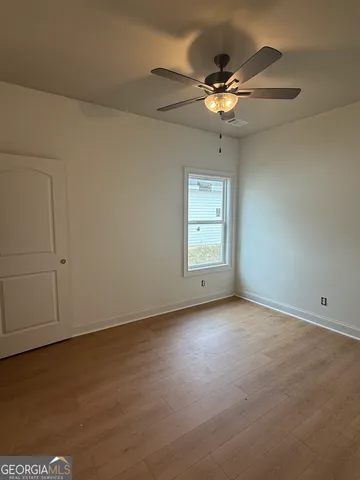 an empty room with a chandelier fan and windows