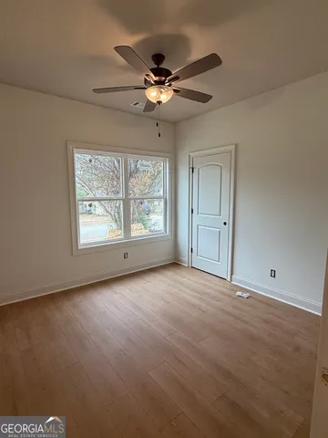 an empty room with windows and ceiling fan