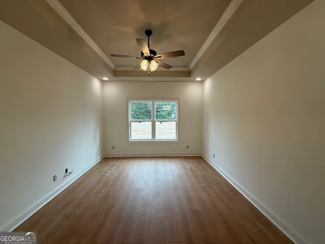an empty room with wooden floor chandelier fan and windows