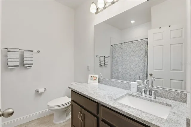 a bathroom with a granite countertop sink a toilet and a mirror