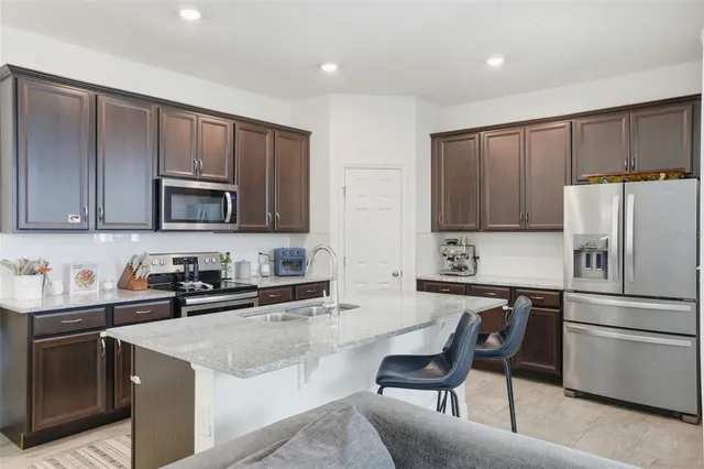 a kitchen with granite countertop a refrigerator stove top oven a sink and dishwasher
