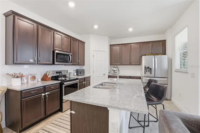 a kitchen with stainless steel appliances granite countertop a stove top oven a refrigerator a sink and a microwave with wooden floor