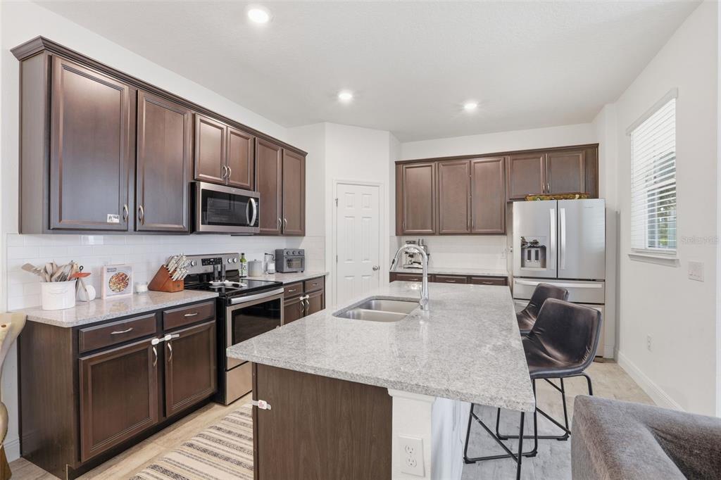 2420 Firstlight Way Winter Park, FL 32792 - Photo 7 of 48 a kitchen with stainless steel appliances granite countertop a stove top oven a refrigerator a sink and a microwave with wooden floor