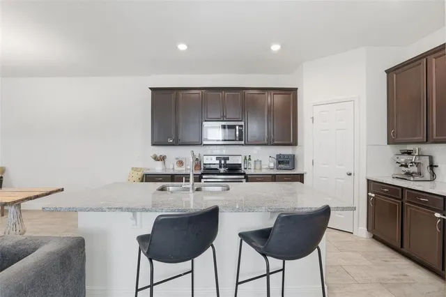 a kitchen with stainless steel appliances granite countertop a stove a sink a microwave a refrigerator and white cabinets