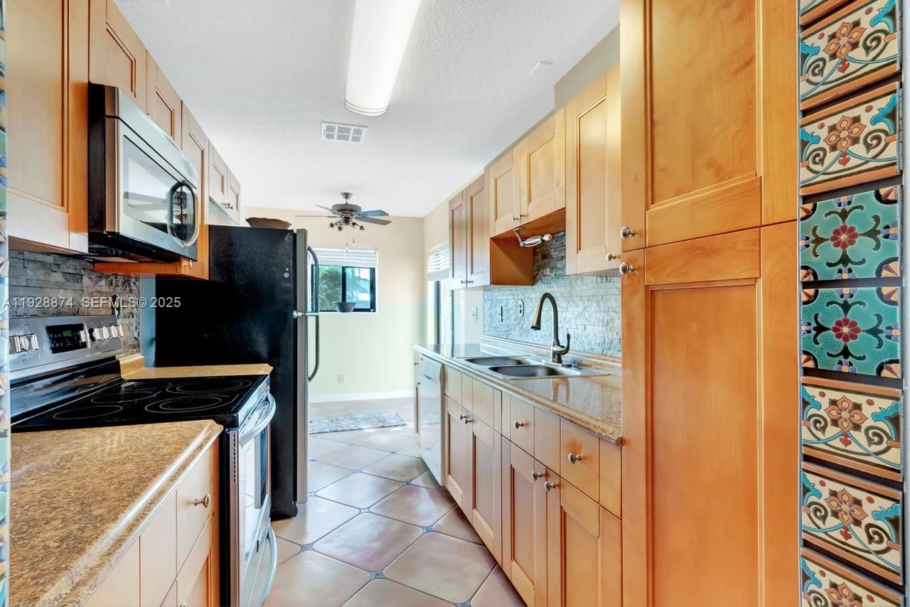 5170 Nesting Way, Unit B Delray Beach, FL 33484 - Photo 7 of 16 a kitchen with stainless steel appliances granite countertop a refrigerator and a stove