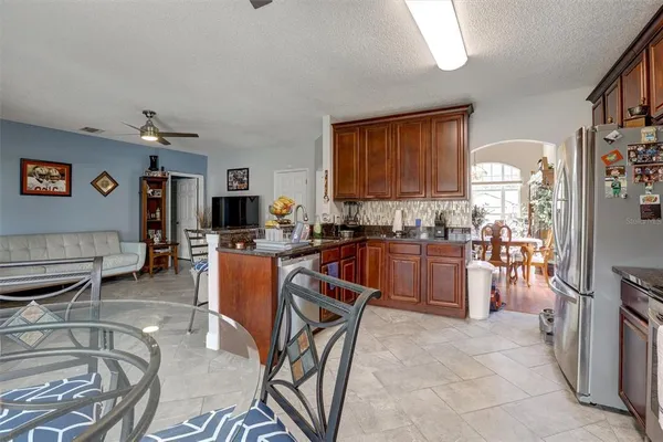 a kitchen with stainless steel appliances granite countertop a refrigerator a stove a sink dishwasher and a dining table with the kitchen view