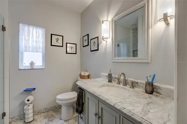 a bathroom with a granite countertop toilet sink and mirror