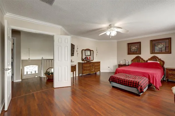 a spacious bedroom with a bed and dresser with wooden floor