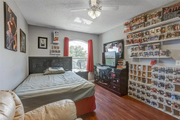 a bedroom with a bed and dresser with wooden floor