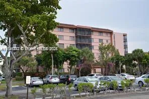 a front view of a building with garden and trees