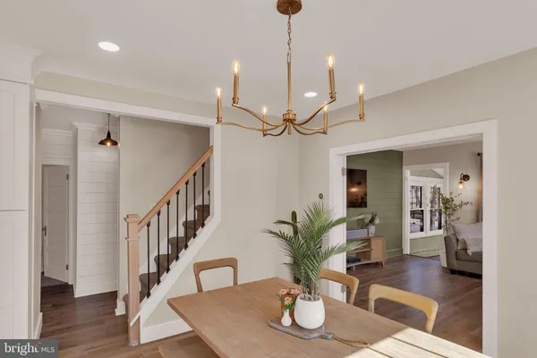 a dining room with wooden floor a chandelier a glass table and chairs