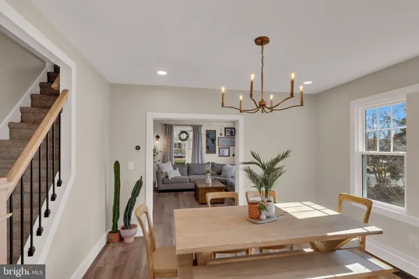 a dining room with wooden floor a chandelier a wooden table and chairs