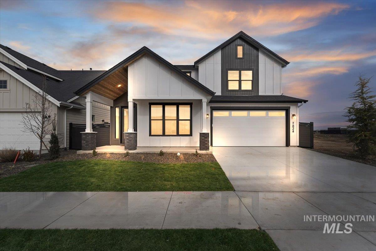 View of front of house with board and batten siding, a garage, a porch, driveway, and a front lawn