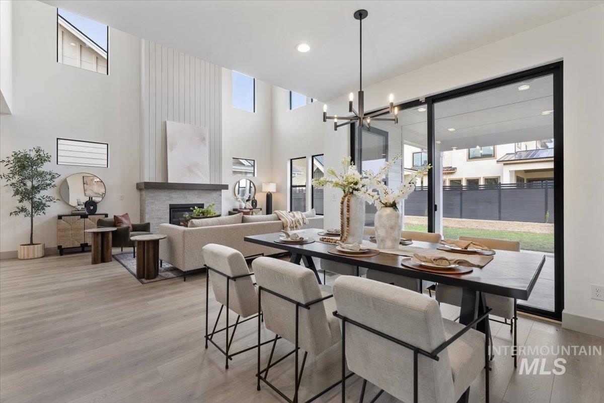 7624 West Old School Street, Unit FREMONT Meridian, ID 83646 - Photo 15 of 35 Dining area with light wood-style flooring, a glass covered fireplace, a high ceiling, and suspended lighting