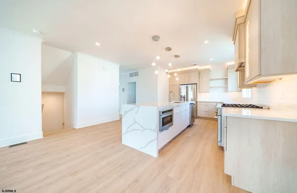 a large kitchen with stainless steel appliances kitchen island a large counter top and a wooden floors