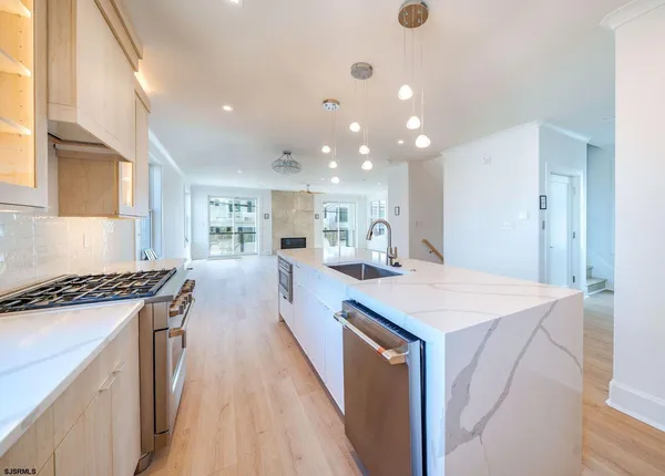 a open kitchen with kitchen island a stove a sink a refrigerator and chairs