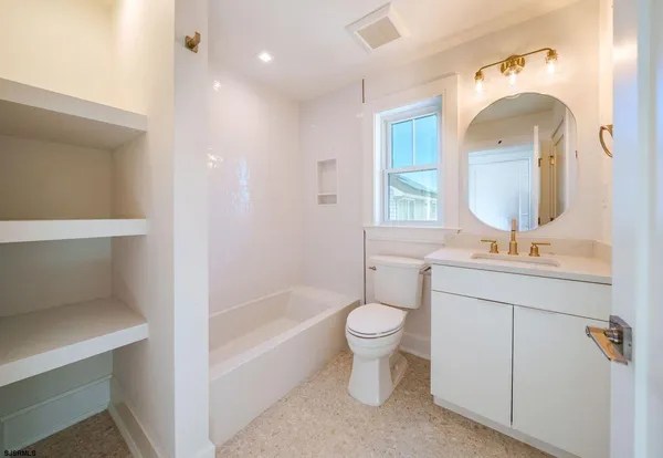 a bathroom with a toilet sink a mirror a bathtub and window
