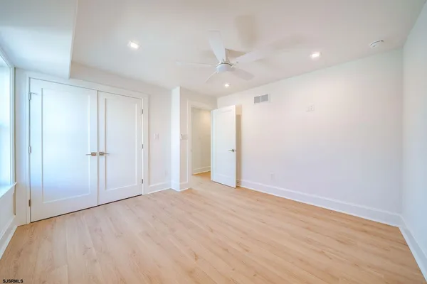 an empty room with wooden floor and ceiling fan