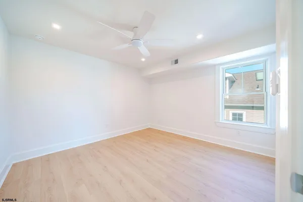 an empty room with wooden floor fan and windows