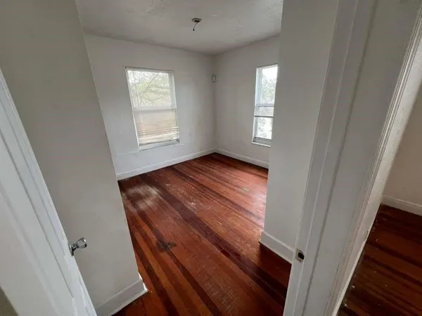 a view of an empty room with wooden floor and a window