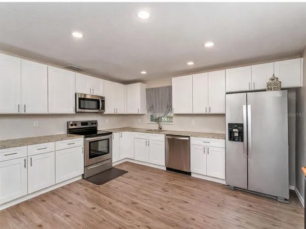 a kitchen with granite countertop white cabinets and stainless steel appliances