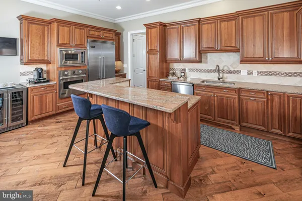 a kitchen with stainless steel appliances granite countertop a stove a sink dishwasher a microwave oven and a dining table with wooden cabinet