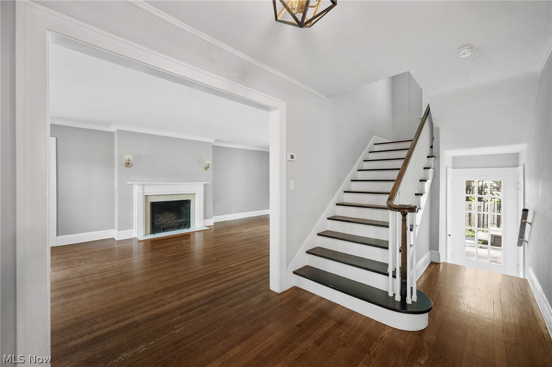 2924 Brighton Road Shaker Heights, OH 44120 - Photo 12 of 31 Stairway featuring wood finished floors, a fireplace with flush hearth, baseboards, and crown molding