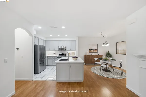 a living room with stainless steel appliances kitchen island granite countertop wooden floor a couch and a view of kitchen