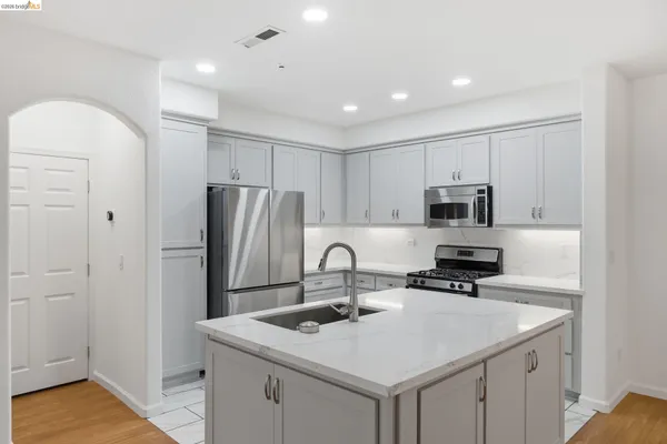 a kitchen with stainless steel appliances granite countertop a sink a stove a refrigerator and cabinets