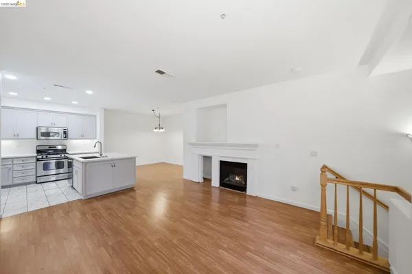 a large kitchen with stainless steel appliances granite countertop a stove top oven a sink and a oven with wooden floors