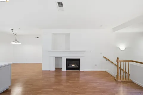a view of empty room with wooden floor and fireplace