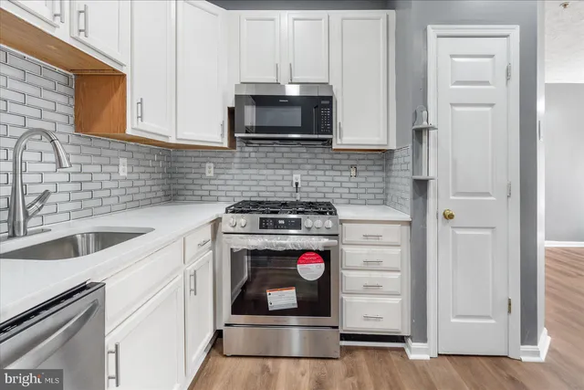 a kitchen with granite countertop white cabinets and stainless steel appliances