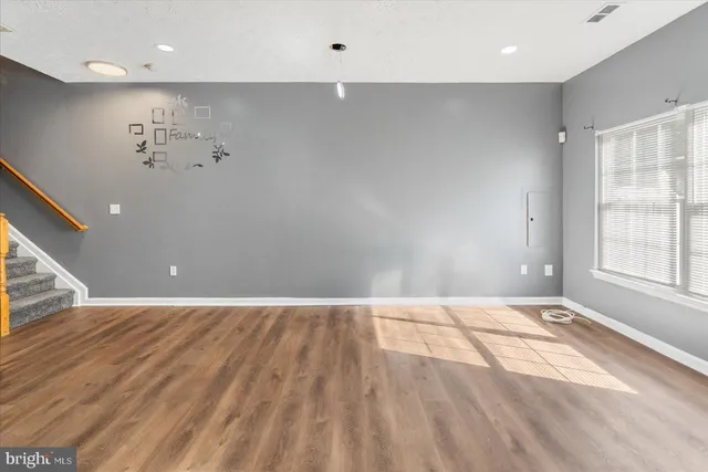 an empty room with wooden floor and windows