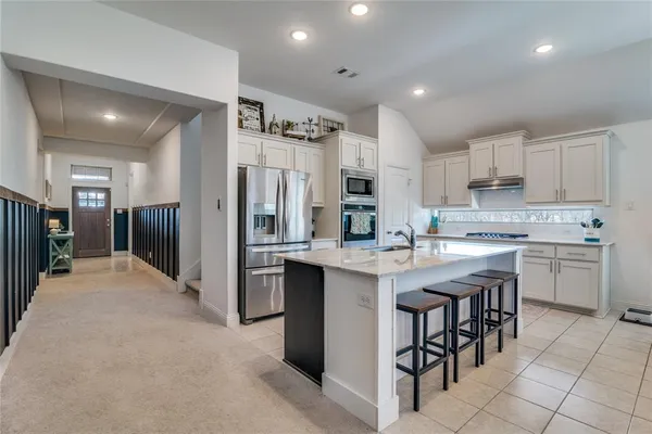 a kitchen with stainless steel appliances granite countertop a refrigerator and a stove top oven